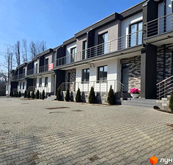 Зовнішній вигляд Котеджного містечка VIVA-CHERNIVTSI. Фасад будинку з балконами та прибудинкова територія з тротуарною плиткою.