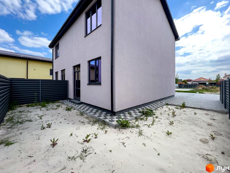 Зовнішній вигляд будинку котеджного містечка КМ Одеський з піщаною прибудинковою територією та парканом.