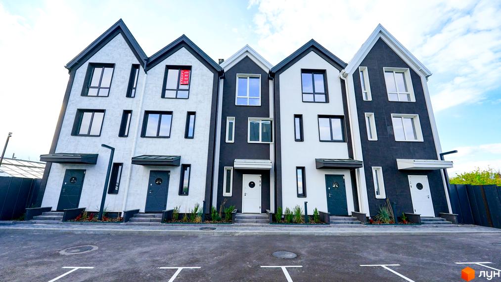 Зовнішній вигляд таунхаусів New Smart 15 з біло-чорними фасадами та індивідуальними входами. Навколо будинків облаштована прибудинкова територія з доріжками та зеленими насадженнями.