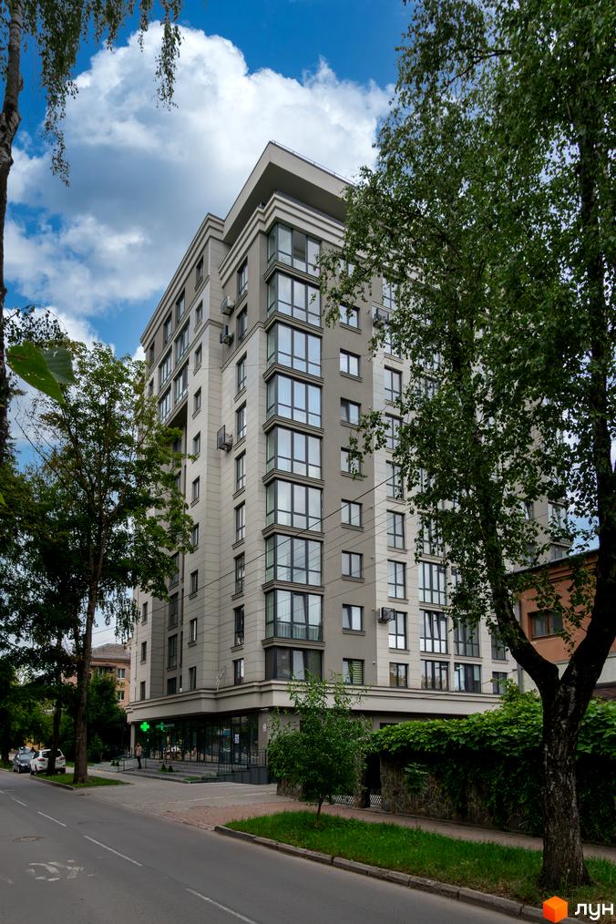 Зовнішній вигляд новобудови ЖК King Hall з великою кількістю вікон та кондиціонерів, оточеної деревами та зеленню.