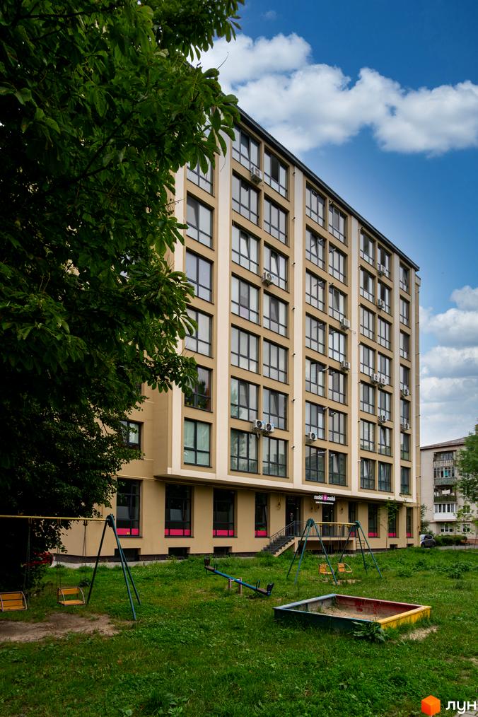 Новобудова nobi nobi на вул. Короля Данила, 11 з бежевим фасадом та великими вікнами. На прибудинковій території зелений газон та дитячий майданчик.