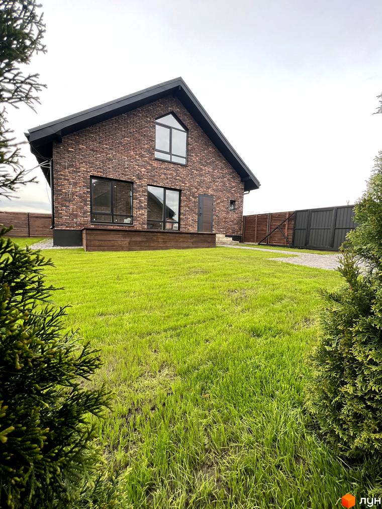 Котеджне містечко КМ Одноповерховий Київ - Віта Поштова: цегляний будинок з великими вікнами та доглянутим газоном. Навколо будинку огорожа та зелені насадження.