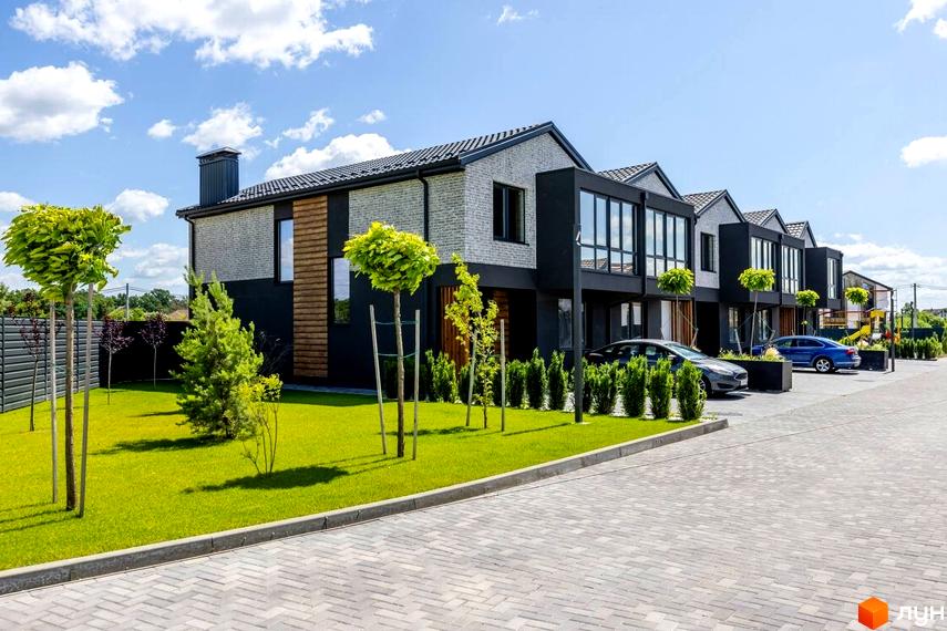 Котеджне містечко Romankiv Village: фасади будинків з сірої цегли та чорних панелей, великі вікна, доглянутий газон та дерева.