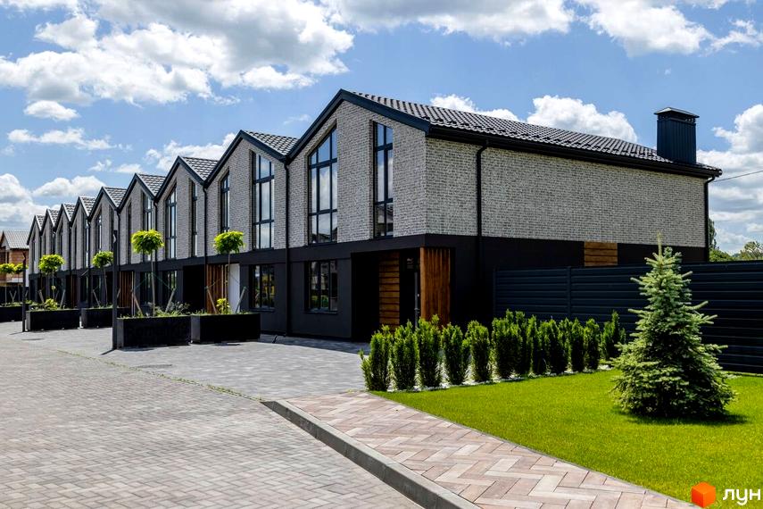 Котеджне містечко Romankiv Village: фасади будинків з сірої цегли та чорної штукатурки, великі вікна, зелені насадження та вимощена територія.