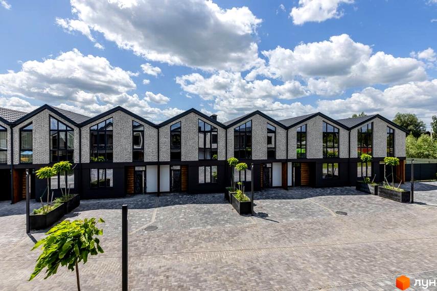 Котеджне містечко Romankiv Village: фасади будинків з сірої цегли та великими вікнами, прибудинкова територія з бруківкою та зеленими насадженнями.