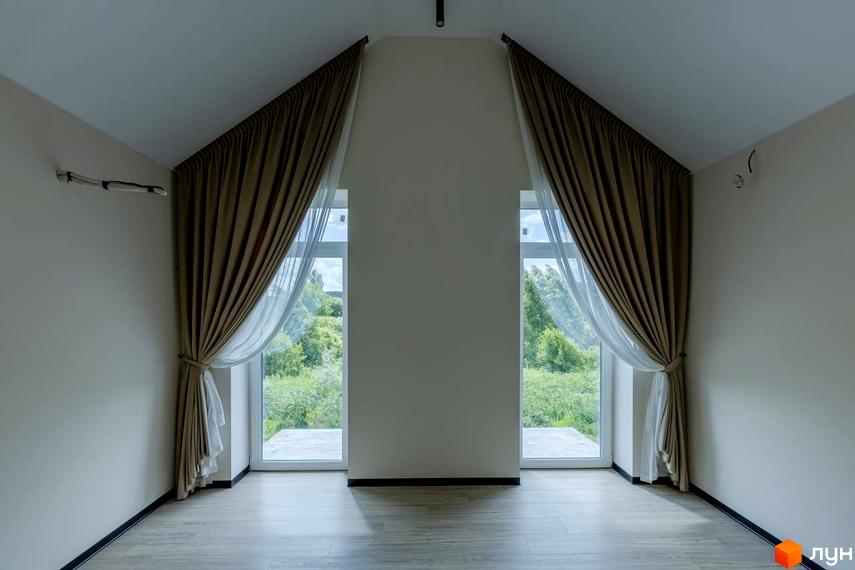 Інтер'єр кімнати з двома великими вікнами, що виходять на зелену територію, в котеджному містечку КМ Romankiv Village. Завіси з тюлем створюють затишок.