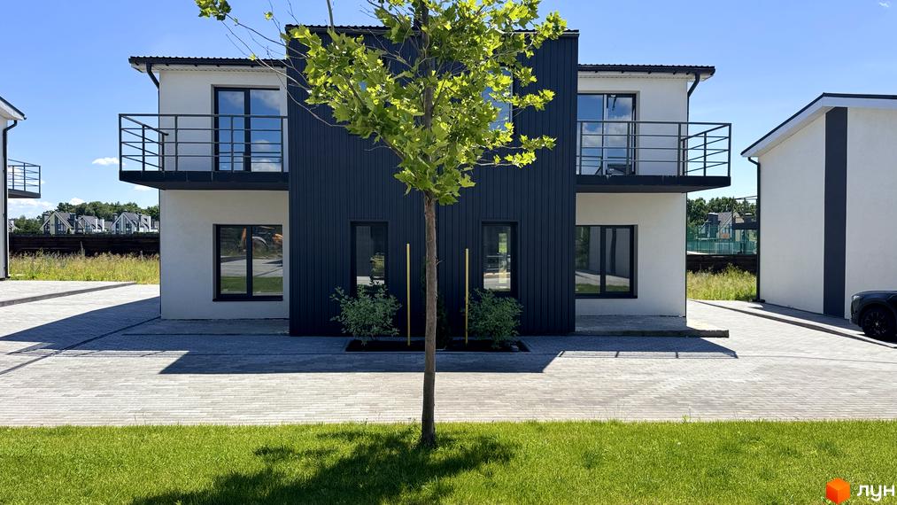 White-Blackie Duplex - новобудова з білими фасадами та темними акцентами, розташована на вимощеній бруківкою території з доглянутим газоном.