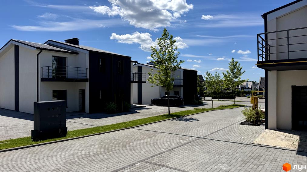 White-Blackie Duplex - новобудова з біло-чорними фасадами та балконами, розташована на вимощеній вулиці з зеленими насадженнями.