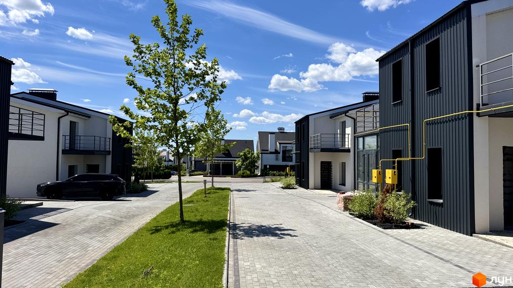 White-Blackie Duplex: сучасні дуплекси з біло-чорними фасадами та доглянутою прибудинковою територією з зеленими насадженнями.