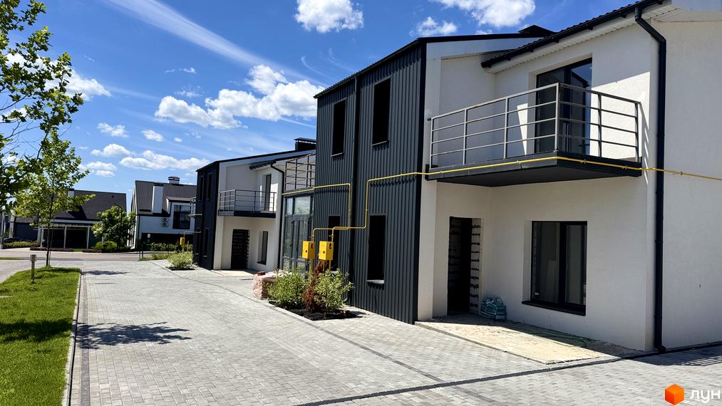 White-Blackie Duplex - новобудова з біло-чорними фасадами та балконами, розташована на брукованій прибудинковій території під блакитним небом.