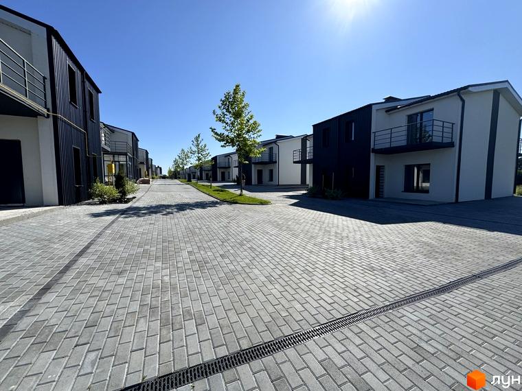 White-Blackie Duplex – новобудова з чорно-білими фасадами та балконами, розташована на вимощеній вулиці з деревами та газоном.