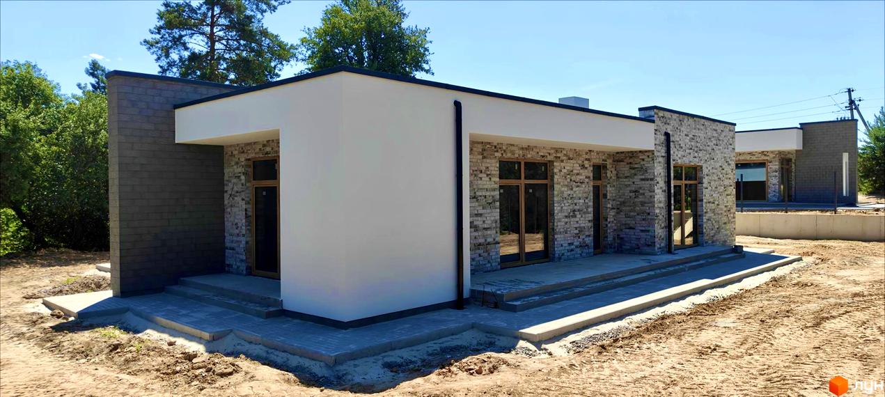 Котеджне містечко LOTUS: одноповерхові будинки з сірим та білим фасадом, вікнами та бруківкою на території.