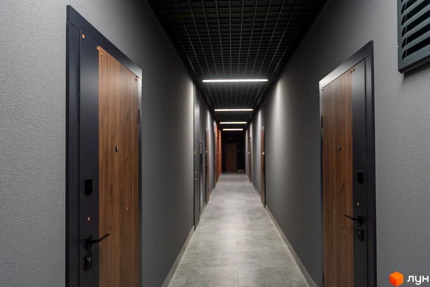 Коридор з дверима в апарт-комплексі Ітака. Сірі стіни, дерев'яні двері з темною фурнітурою та підвісна стеля з освітленням.