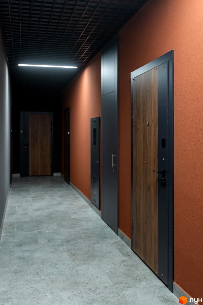 Коридор з дверима в апарт-комплексі Ітака. Сіра підлога та теракотові стіни створюють затишну атмосферу.