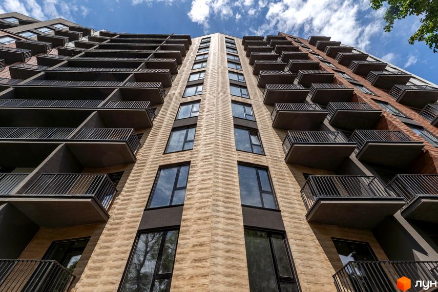 Зовнішній вигляд багатоквартирного будинку Апарт-комплекс Ітака з численними балконами та вікнами на тлі блакитного неба з хмарами.