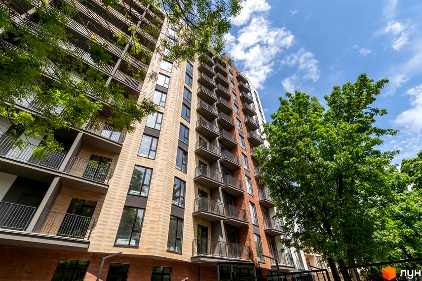 Апарт-комплекс Ітака - це висотна будівля з балконами та великими вікнами, оточена зеленню дерев.