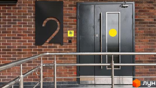 Фасад житлового комплексу Стандарт з номером 2 біля входу. Цегляна будівля з металевими поручнями.