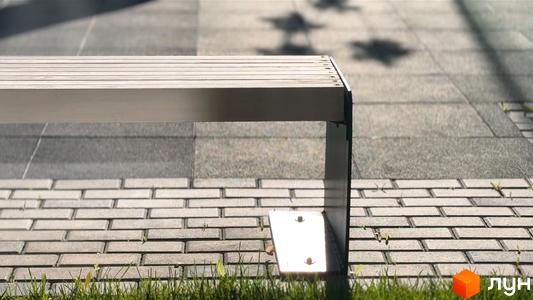 Фото лавки біля тротуару з плитки. Будівельний проєкт Стандарт має зручні місця для відпочинку на території.