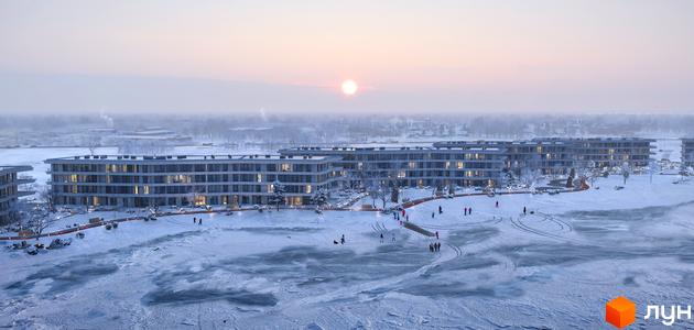 Житловий комплекс Park Lake City: світлі будинки на березі замерзлого озера в зимовий день, з людьми на снігу та льоду.
