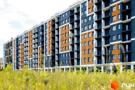 Новобудова ЖК КЕЛЬЦЕ з помаранчевими та синіми фасадами, балконами та зеленою травою на передньому плані.