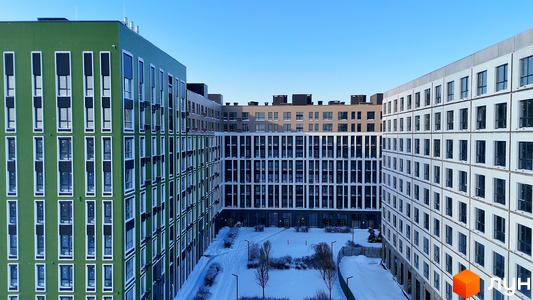 Житловий комплекс PARK ROYAL з зеленими та білими фасадами, вікнами та балконами, на тлі блакитного неба. На прибудинковій території взимку видно сніг, дерева та ліхтарі.