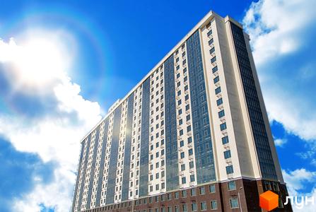 Житловий комплекс Двадцята Перлина: високий багатоповерховий будинок з бежевим фасадом, великими скляними вікнами та темною основою.