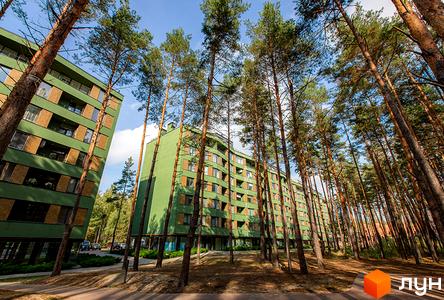 Зелений багатоповерховий будинок ЖК Park Town серед високих дерев. На території комплексу є доріжки та зелені насадження.