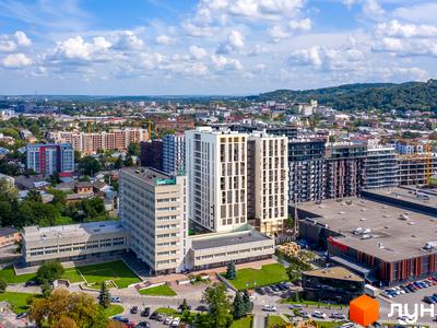 WELL towers – апарт-комплекс з білими фасадами та скляними балконами, розташований поруч із зеленим парком та торговим центром.