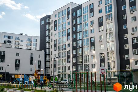 Зовнішній вигляд Житлового кварталу CONTINENT: багатоповерховий будинок з великою кількістю вікон та дитячим майданчиком на прибудинковій території.