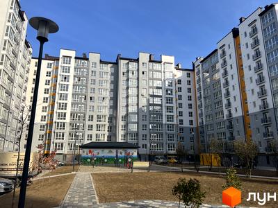 Житловий комплекс Квартал Галицький: багатоповерхові будинки сірого та білого кольору з балконами, внутрішній двір з дитячим майданчиком.