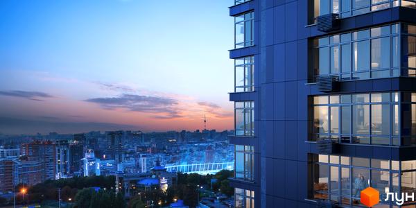 Зовнішній вигляд новобудови ЖК Maxima Residence на тлі вечірнього міста. Сучасний житловий комплекс з панорамними вікнами та балконами.
