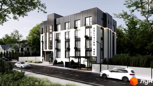 Комплекс Coliving One з білою та чорною фасадною обробкою, великими вікнами та балконами. Поруч дорога з автомобілями та зелені насадження.