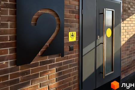 Житловий комплекс Стандарт: вхідна група з дверима та номером 2 на цегляній стіні.