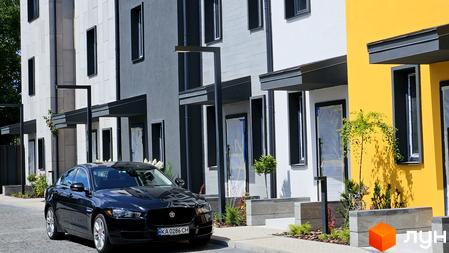 Таунхауси New Smart 9 з чорним авто на тлі біло-жовтих будинків. Зовнішній вигляд таунхаусів та прибудинкова територія.