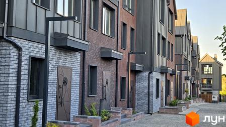 Фасад таунхаусів New Smart 17 з цегляним оздобленням та металевими елементами. Прибудинкова територія з бруківкою та зеленими насадженнями.