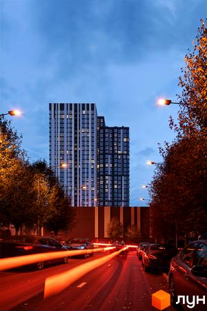 Житловий комплекс Avalon Up з фасадом у смужку та освітленою вулицею з автомобілями ввечері. Навколо багато дерев з осіннім листям.