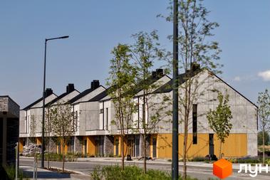 Котеджне містечко О.Краса: сучасні будинки з сірими фасадами та жовтими вставками, зелені дерева та доглянута прибудинкова територія.