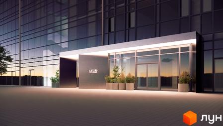 Вхід до новобудови Circle hotel&apartments зі скляним фасадом, що відбиває небосхил. Прибудинкова територія прикрашена рослинами у вазонах.