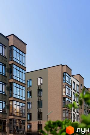 Новобудова Комфортне містечко Residence з цегляними та сірими фасадами, великими вікнами та балконами. Навколо зелені дерева.