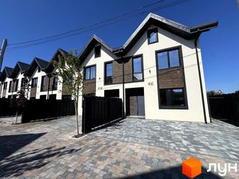 Ряд двоповерхових таунхаусів 40 Estates зі світлими фасадами та темними дахами. Перед будинками викладена бруківка та встановлені чорні огорожі.