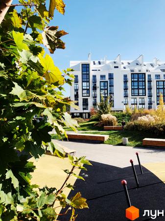 Зображення будинку в Житловому комплексі City Lake. На передньому плані зелені насадження та дитячий майданчик.