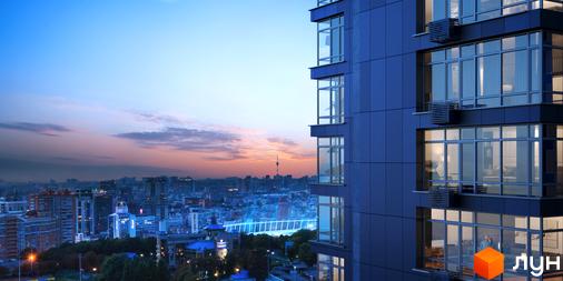 Зовнішній вигляд новобудови ЖК Maxima Residence на тлі вечірнього міста. Сучасний житловий комплекс з панорамними вікнами та балконами.