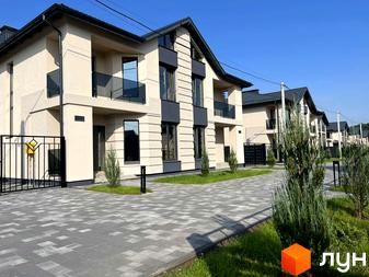 Котеджне містечко КМ Beverly Hills Residence: двоповерхові будинки світло-бежевого кольору з темними елементами фасаду, скляними балконами та вимощеною плиткою прибудинковою територією.