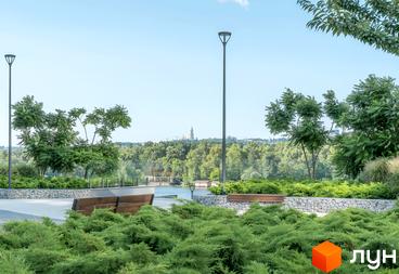 На фото зображено частину житлового комплексу Русанівська Гавань. Видно лавки, ліхтарі та зелені насадження на території біля води.