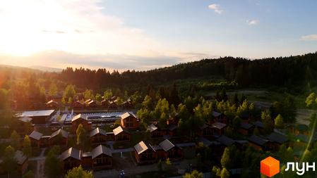 Котеджне містечко KM PHOENIX MEDICAL RESORT з дерев'яними будиночками та басейном на фоні лісу. Територія комплексу оточена зеленню та деревами.