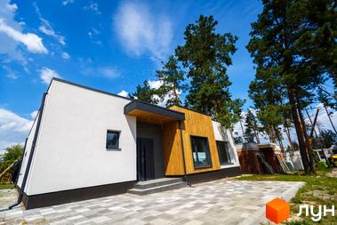 Сучасний житловий комплекс VISION з білою фасадною штукатуркою та дерев'яними елементами. Навколо будинку облаштована прибудинкова територія з бруківкою та зеленими насадженнями.