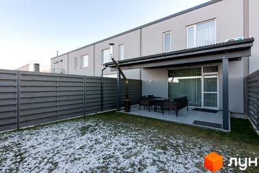 Котеджне містечко Balaton Village: сіра стіна двоповерхового будинку з терасою, вуличними меблями та газоном зі снігом. Огороджена територія з дерев'яним парканом.