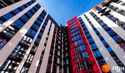 Фасад новобудови ЖК Manhattan Up з червоними та білими елементами, багато вікон та балконів.