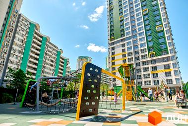 Житловий комплекс Паркове місто: багатоповерхові будинки з яскравими фасадами та просторий дитячий майданчик з ігровими конструкціями.
